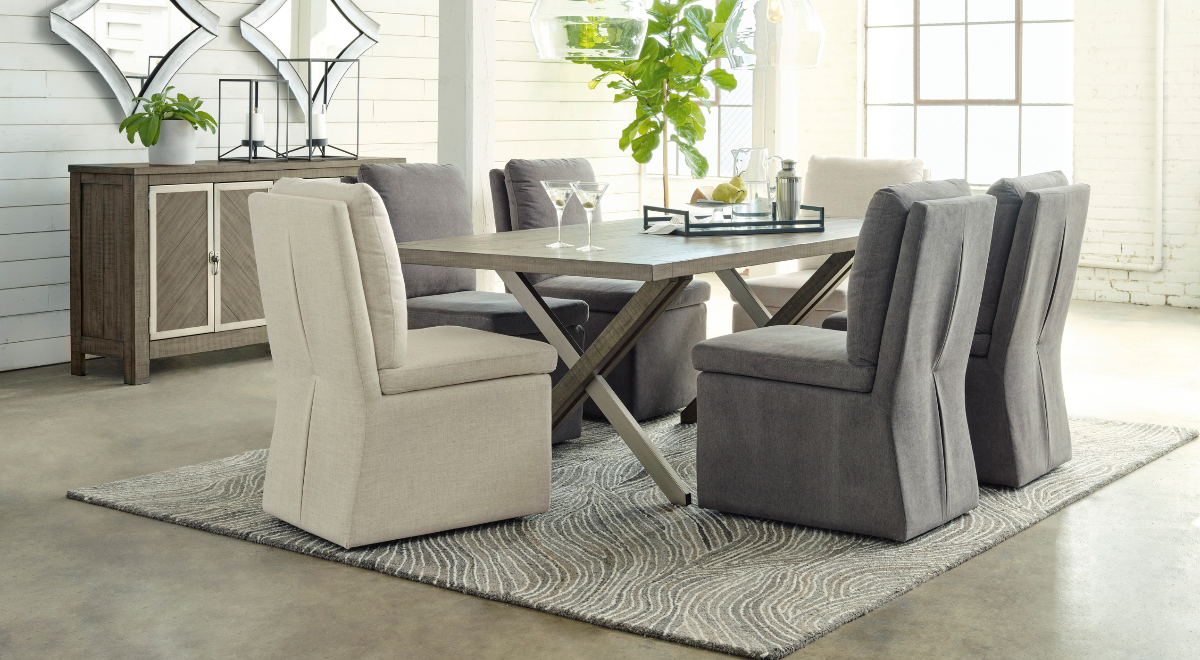Dining room with a table and chairs on a rug, featuring a sideboard and plants.